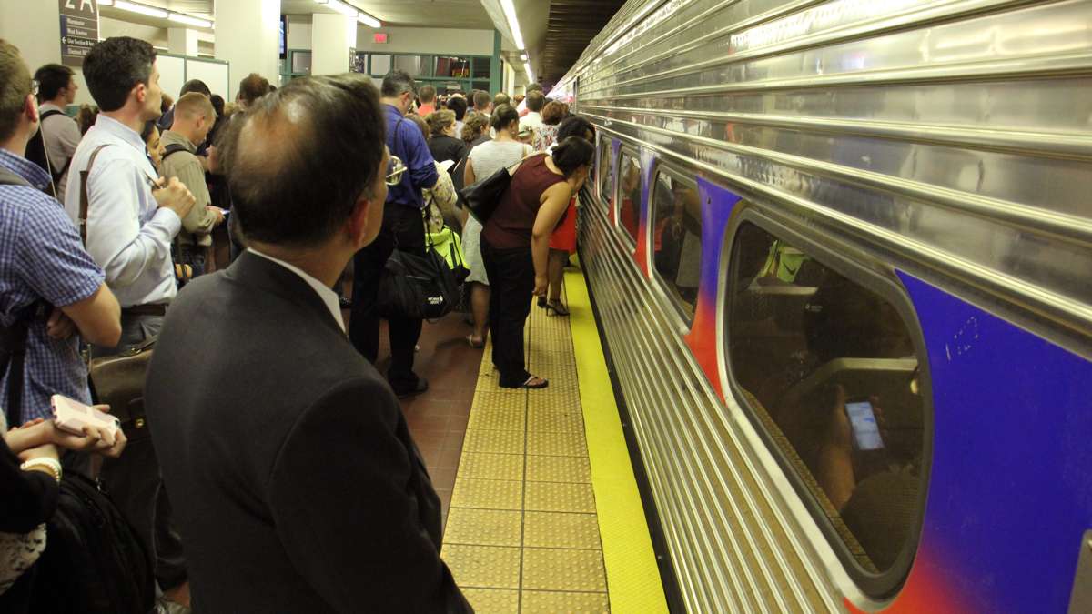 Regional rail passengers at Suburban Station peer through the windows of a rail car too crowded to take them on. (Emma Lee/WHYY)