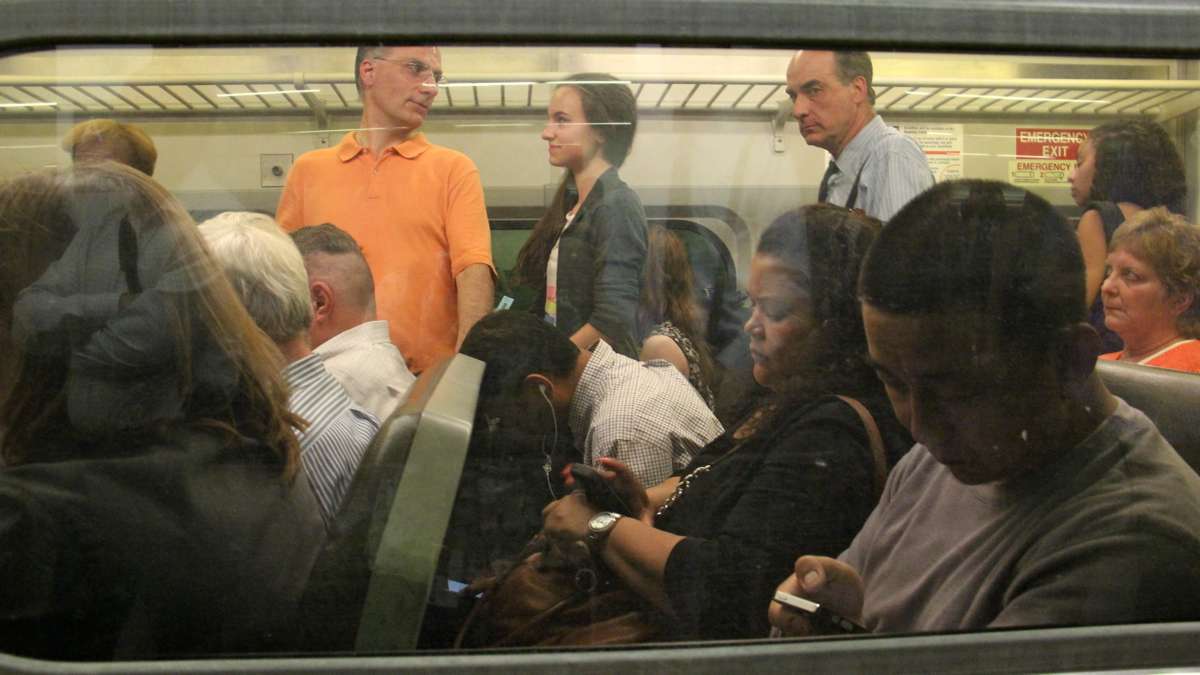 Passengers sit three to a seat and fill the aisles on a SEPTA regional rail car. (Emma Lee/WHYY)