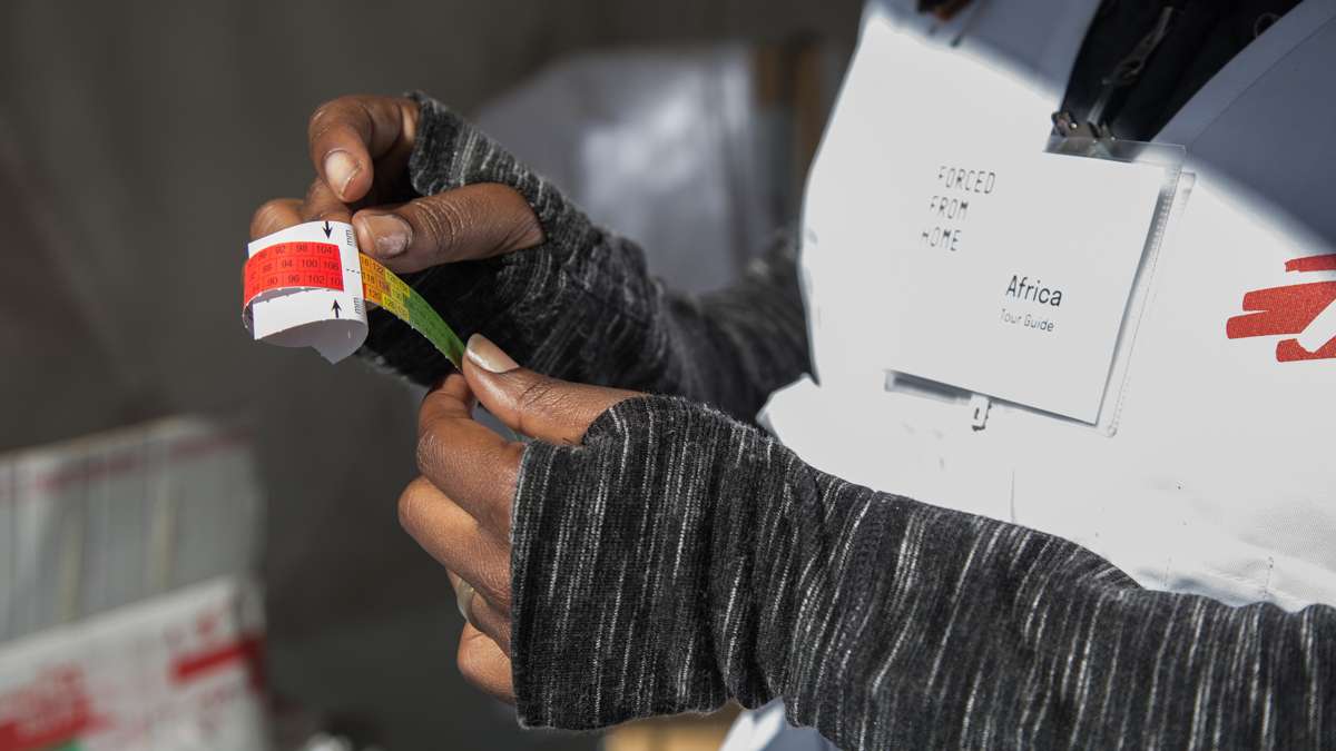 Dr. Africa Stewart shows how to use a MUAC tool, middle upper arm circumference, which is used for determining malnutrition in children who reach MSF aid encampments.