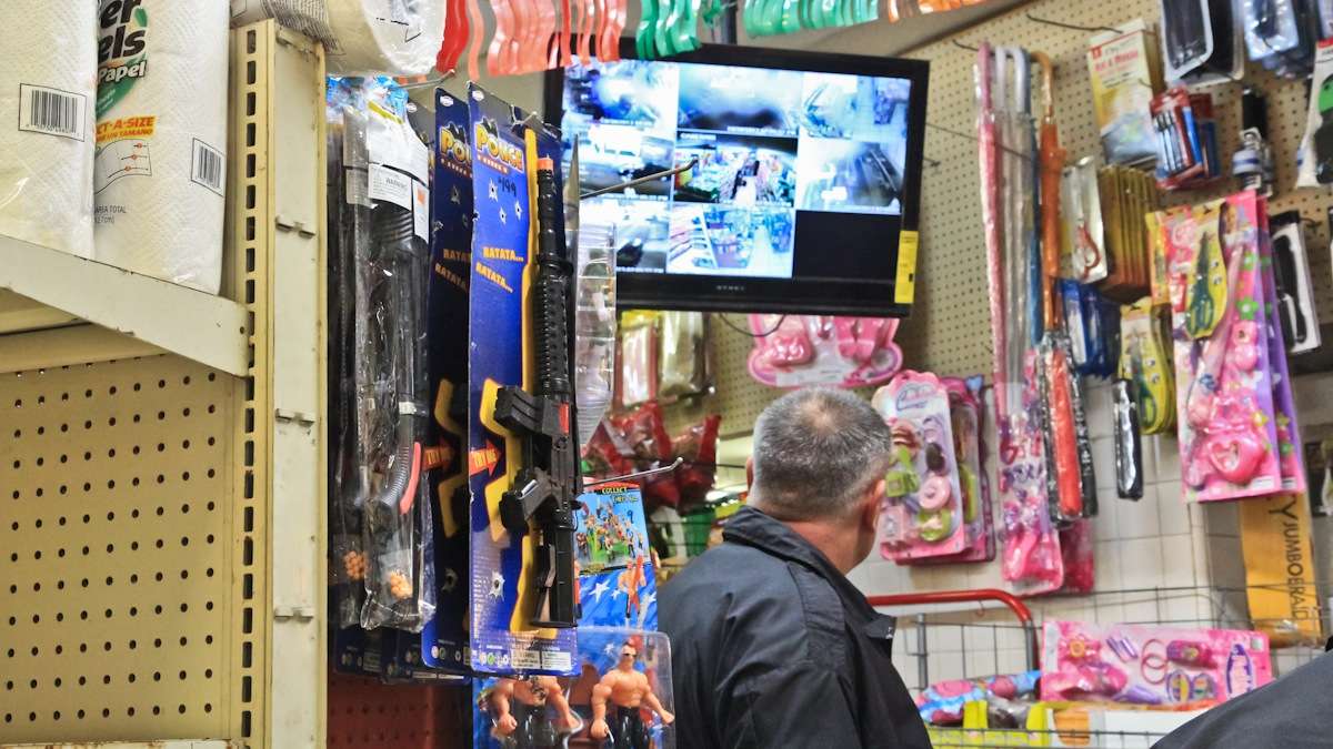 Officers and store owners review security footage at the Gonzalez Mini Mart to positively identify the suspect. (Kimberly Paynter/WHYY)
