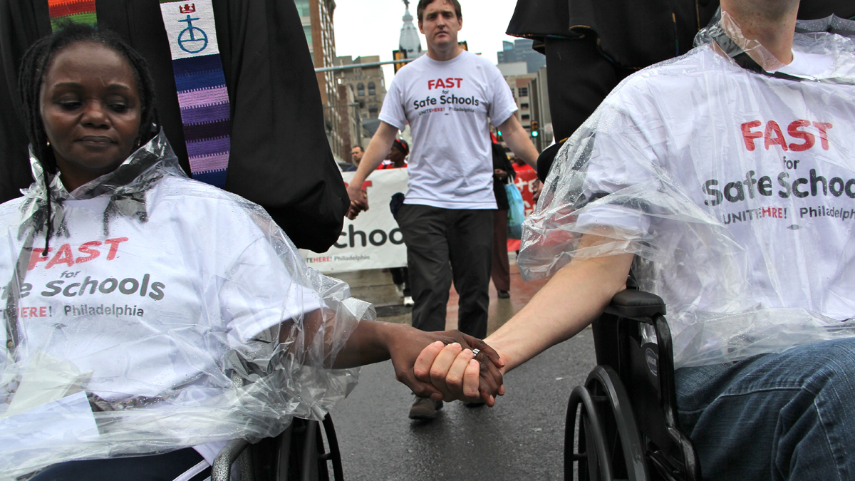  Hunger strikers hold hands as they make their way down Broad Street toward the school administration building, where they would break their fast. (Emma Lee/for NewsWorks) 