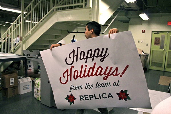 <p>Jacob Alvarez carries a freshly printed window sign to the table at Replica print shop in Center City. (Emma Lee/for NewsWorks)</p>
