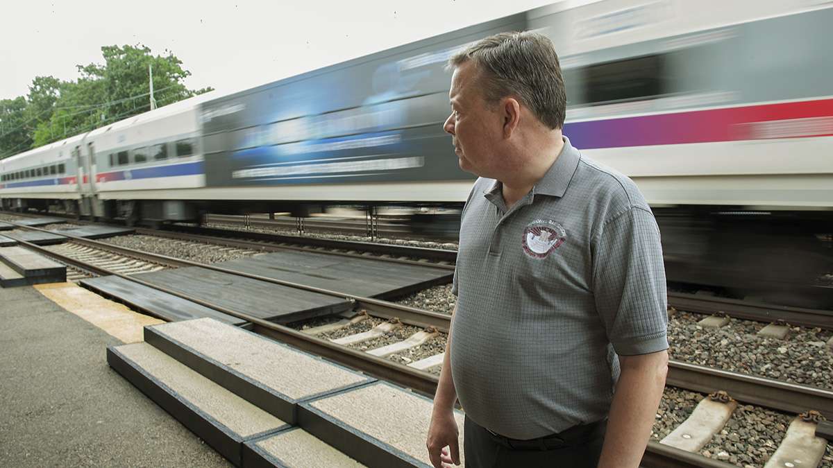 Ardmore Station ticket agent Bill Cairns watches a SEPTA train bypass the station. Several trains bypassed the station because they were already filled to capacity. (Jonathan Wilson for WHYY)