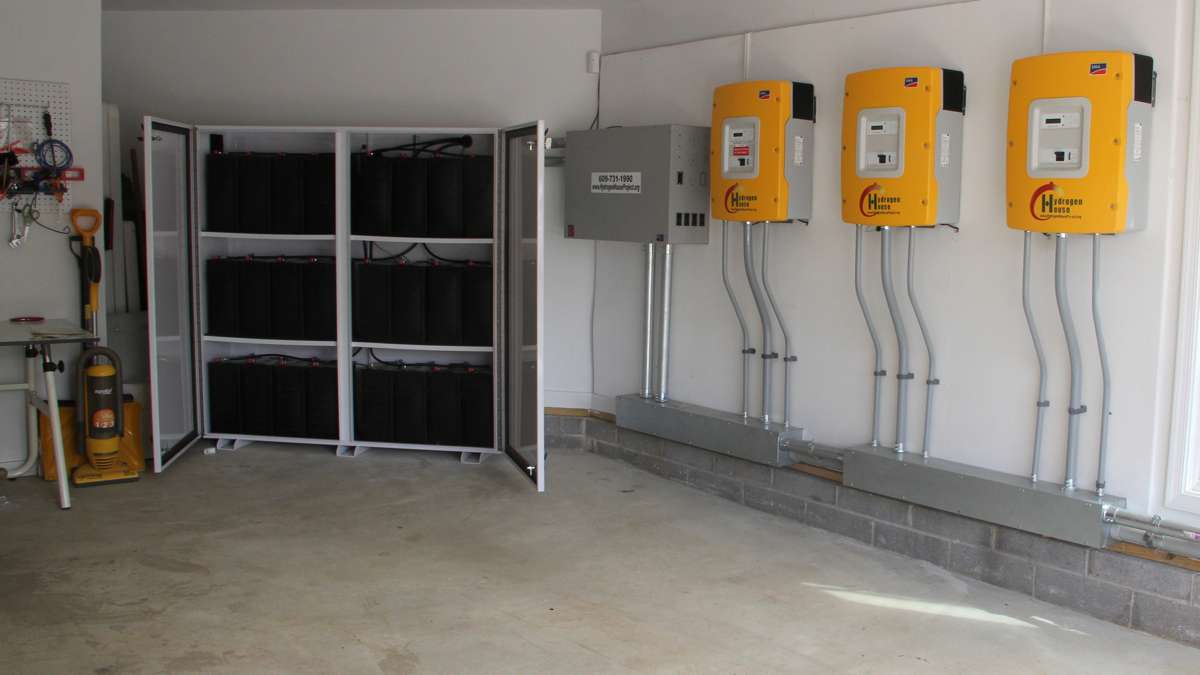 In the garage, batteries (left) store energy while a series of panels regulate the flow between the solar panels, the hydrogen tank and the house. The system also sells energy back to the grid once its own needs are met. (Emma Lee/WHYY)