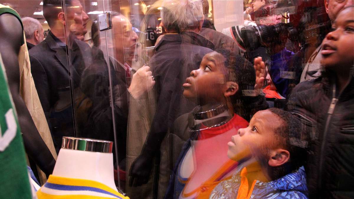 Young visitors gaze into a case full of game-worn NBA basketball jerseys. (Emma Lee/WHYY)
