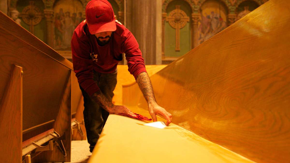 Brett Boulden with Knapp Masonry, tries to keep up on the dust in the pews, which is from all the work resorting the church. (Nathaniel Hamilton/for NewsWorks)