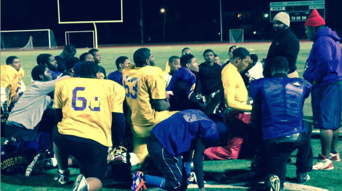 After Thursday's practice at Benjamin Johnston Memorial Stadium, MLK Cougars Head Coach Ed Dunn tells his players that they won't be allowed to play in the Thanksgiving game if they don't bring coaches their report cards. (Brian Hickey/WHYY)