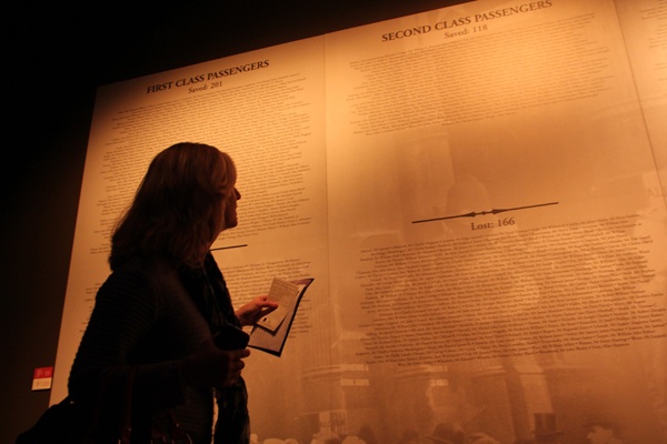 Joanne Concepcion, chaperoning a group of 5th graders from Meredith Elementary School, tries to find the name on her boarding pass in the list of passengers and crew that concludes the exhibit. (Emma Lee/for NewsWorks)