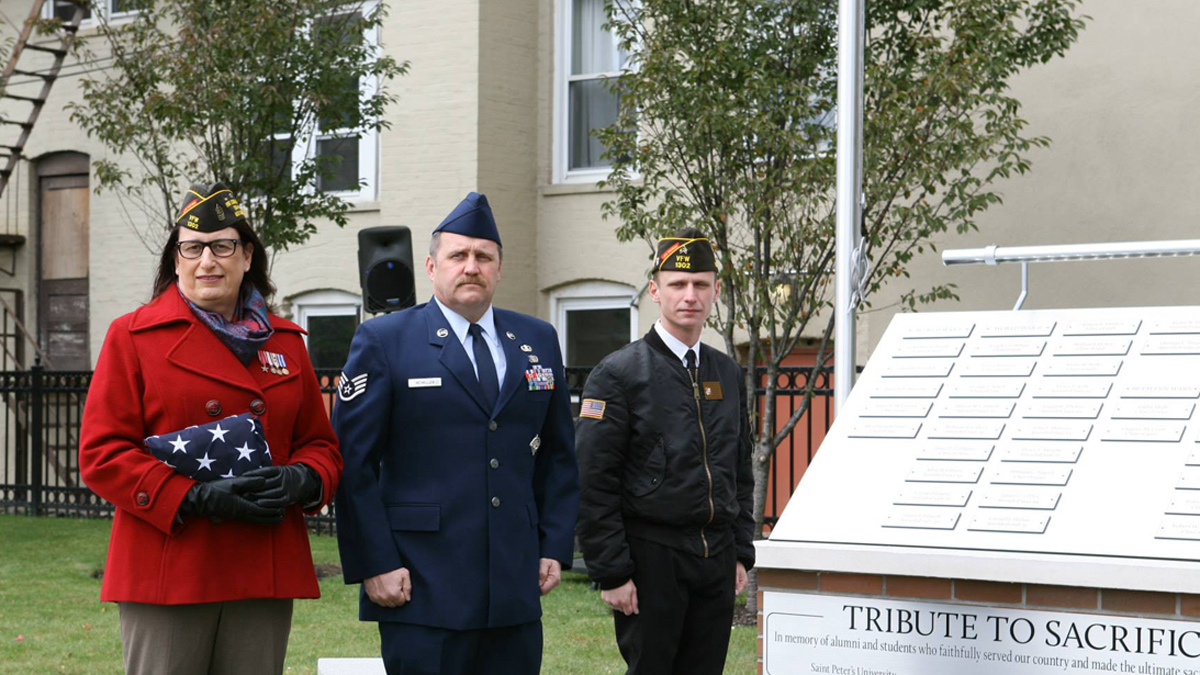 Jennifer Marie Long, (left), holds a flag during a ceremony in November 2014 dedicated to alumni of Saint Peter's University in Jersey City, New Jersey, who are veterans. (Provided) 