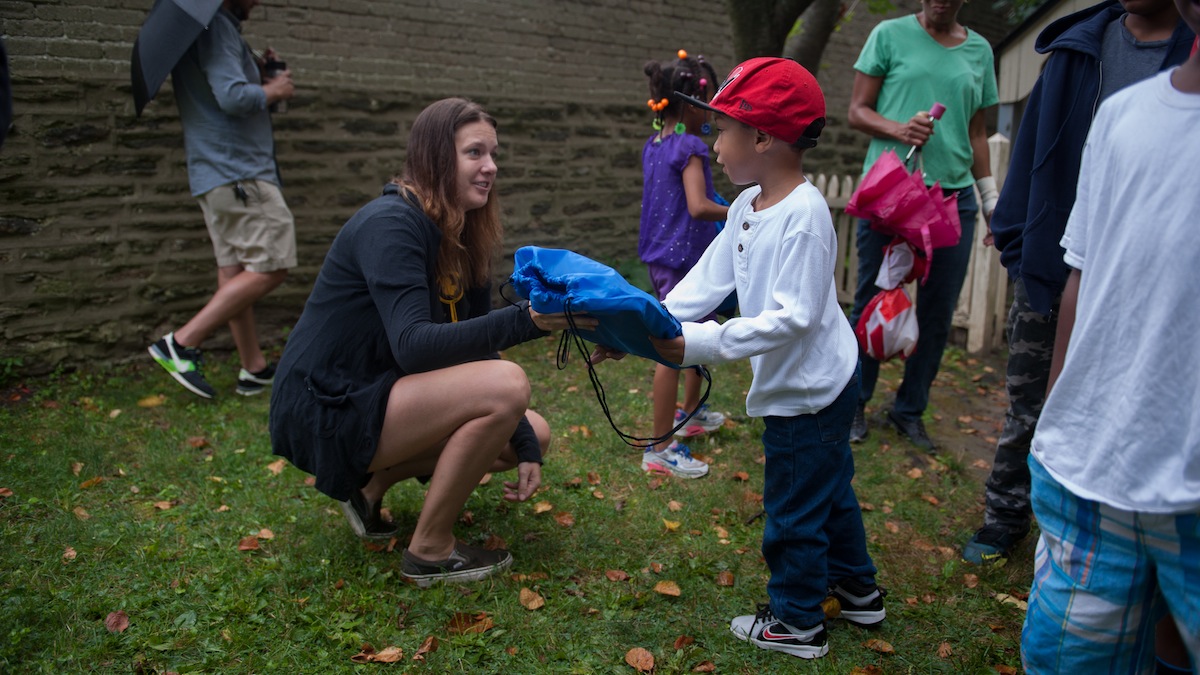 Jayden Hughes, 5, of Allegheny, receives a backpack from volunteer Jessica Hagen, of Mt. Airy, during a back-to-school giveaway at Concord School House Saturday morning in Germantown.