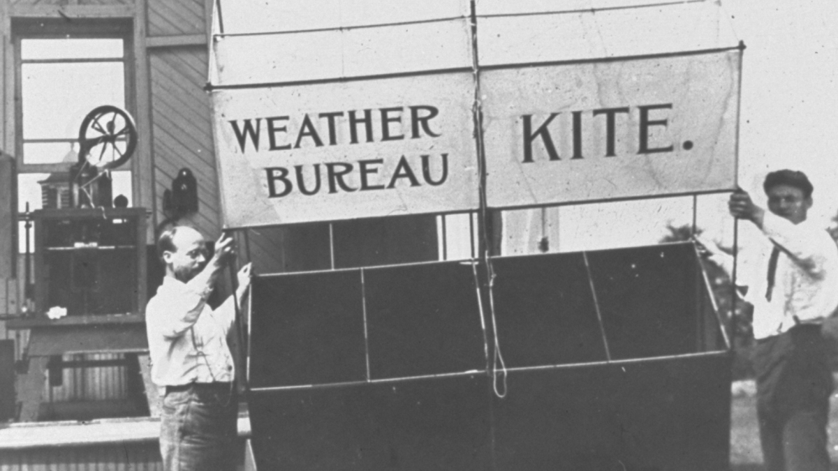 Around 1910, observers prepared to launch this Weather Bureau kite, which would be anchored by the kite-reel house in the background. (Photo via NOAA Photo Library)