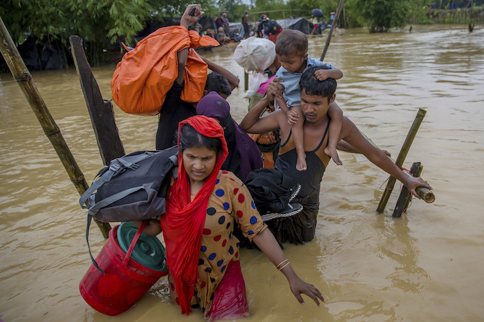 In this file photo, Rohingya Muslims, who crossed over from Myanmar into Bangladesh, use a makeshift footbridge as they carry their children and belongings after their camp was inundated with rain water near Balukhali refugee camp, Bangladesh, Tuesday, Sept. 19, 2017. With a mass exodus of Rohingya Muslims sparking accusations of ethnic cleansing from the United Nations and others. (Dar Yasin/AP Photo)