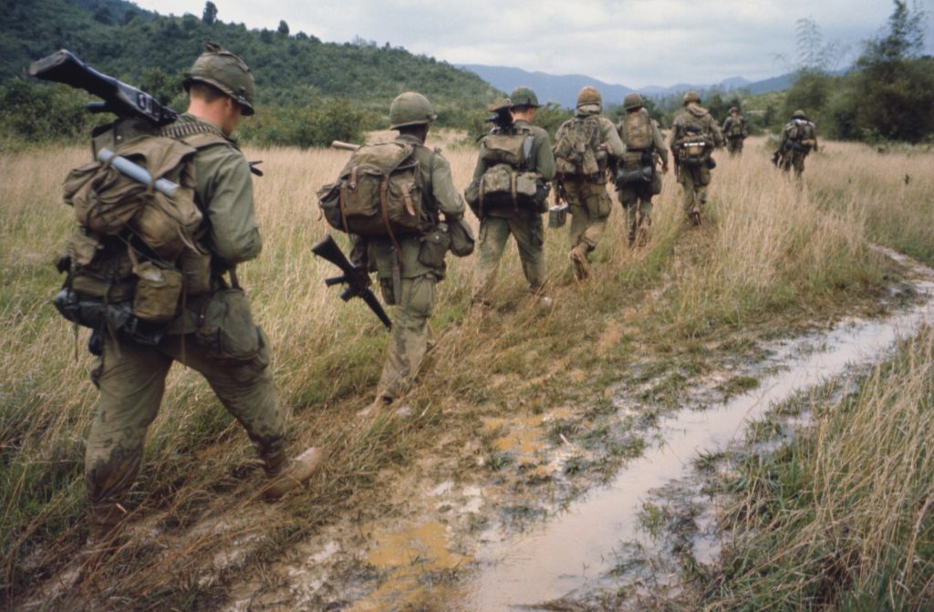 Soldiers are walking through a muddy field in Vietnam on a search and destroy operation