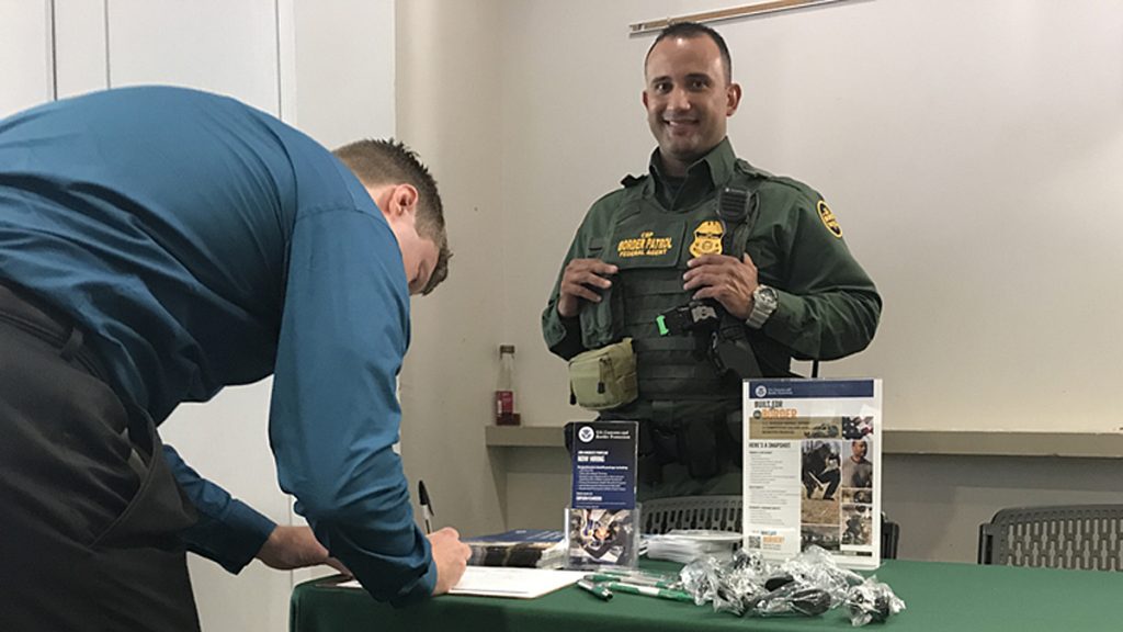 borderpatrolx1200 Border Patrol Agent Lanllony Molina of Erie, Pennsylvania, smiles as a job-seeker gives his information during an employment fair Thursday at Temple University. (Laura Benshoff/WHYY)