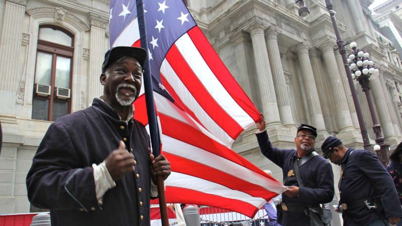 A members of the 3rd Regiment United States Colored Troops re-enactors unfurl a Civil War era flag at the dedication of the monument to Octavius Catto at Philadelphia City Hall