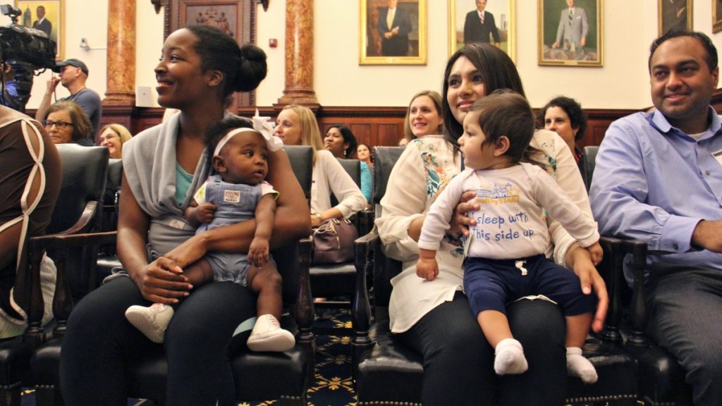 l_2017-09-26-e-lee-philadelphia-city-hall-aarav-vyas-aasta-mehta-jasmine-pitt-leilani-mitchell-safe-sleeping-campaign-for-infants Nine-month-old Aarav Vyas (right) wears a shirt with the slogan ''I sleep with this side up.'' He and his mother, Aasta Mehta, along with Jasmine Pitt-Mitchell and her 6-month-daughter, Leilani (left) helped to kick off Philadelphia's safe sleeping campaign. (Emma Lee/WHYY)