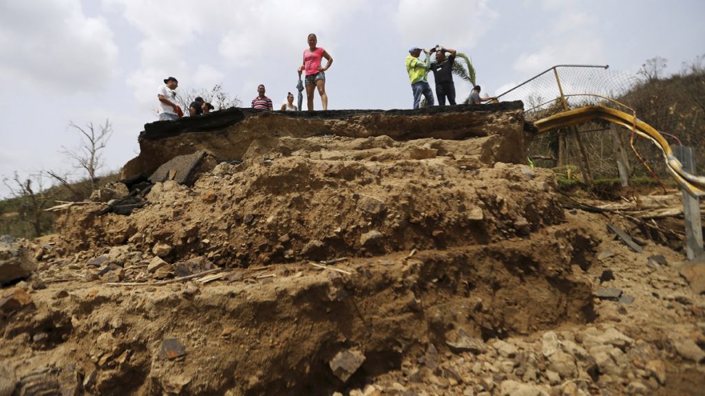 l_ap_17272567705273 Residents Wednesday look over the edge of a bridge that was swept away by Hurricane Maria
