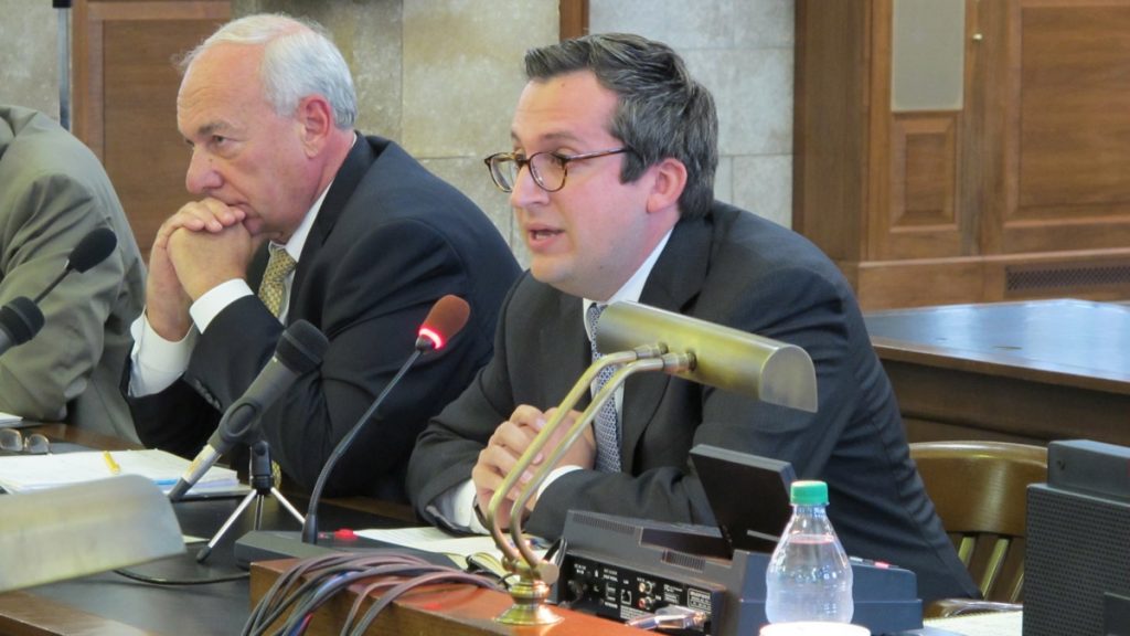 l_ptc Two men sit at a table, testifying, in front of microphones