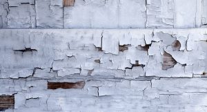 Distressed building wall with white aged paint chipping off