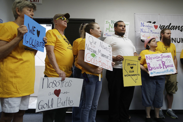 People hold up signs during a news conference by supporters of the Basin and Range and Gold Butte National Monuments, Monday, July 31, 2017, in Las Vegas. The supporters held the news conference after Interior Secretary Ryan Zinke cancelled a meeting with Gold Butte advocates scheduled for Monday. (AP Photo/John Locher)