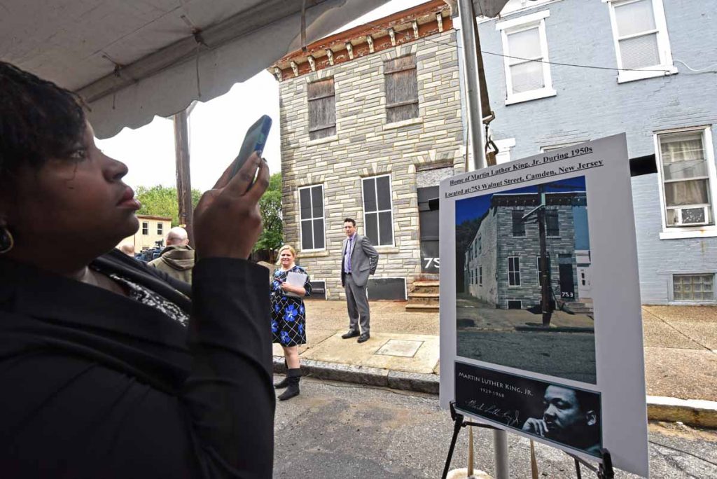05 At the September 2016 press conference to announce the preservation of the house at 753 Walnut Street where Martin Luther King, Jr. stayed, a woman photographs a poster; the house is in the background. (April Saul/for WHYY)