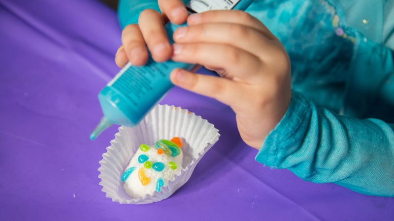a child applies blue icing to a sugar skull