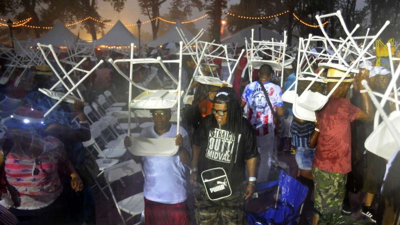 Audience members upend their folding chairs in an attempt to avoid the worst of a heavy downpour between sets at the Welcome America concert on the Parkway.