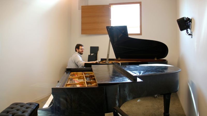 A piano tuner works in one of the practice rooms at the New Music Building. (Emma Lee/WHYY)