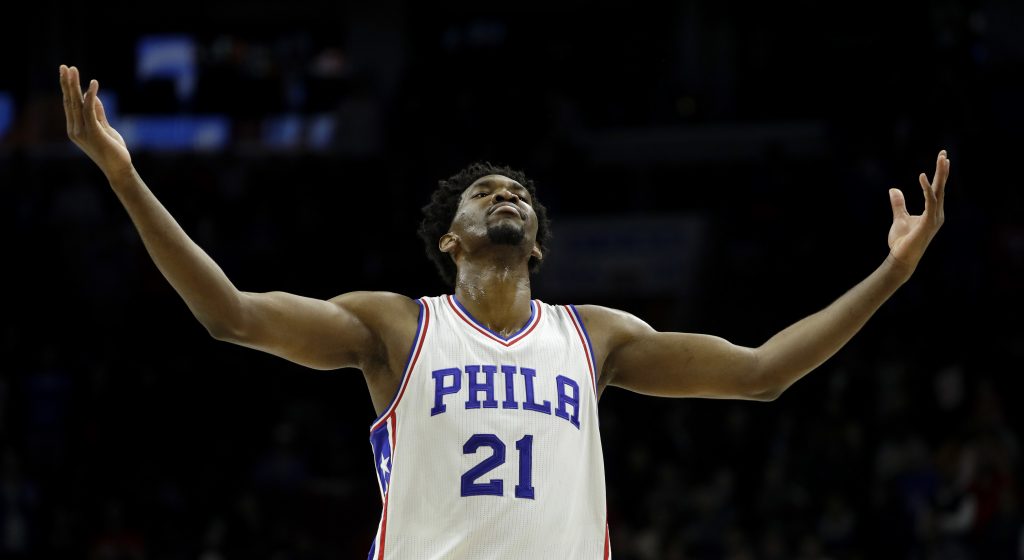 Joel Embiid 7 feet 2 inch- basketball star, Joel Embiid, number 21, in Sixers uniform, arms spread wide, looking up