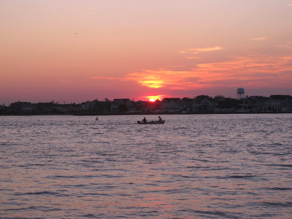 Barnegat Bay-Pollution Sunset, a pink sky, and a small boat on Barnegat Bay