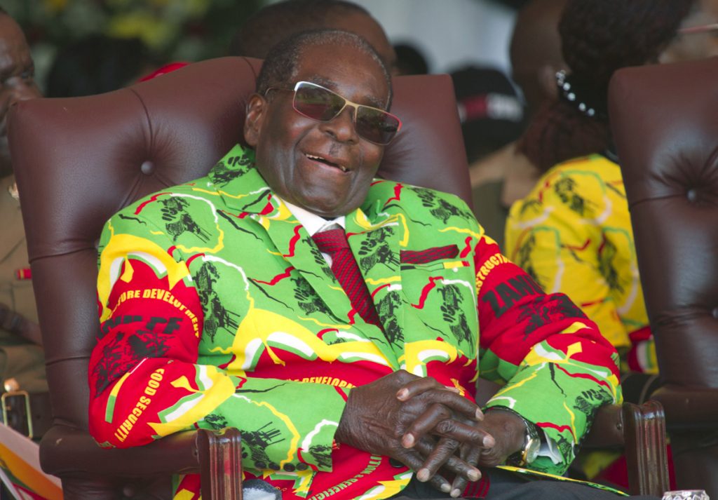 Zimbabwe Mugabe Health Zimbabwean President Robert Mugabe sits in a chair, sunglasses and a smile, wearing a colorful yellow, red, and green jacket
