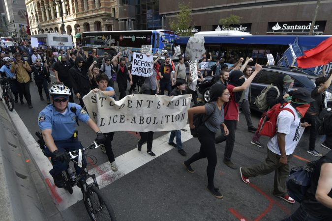 Protesters march through the city streets, some masked, some carry a banner