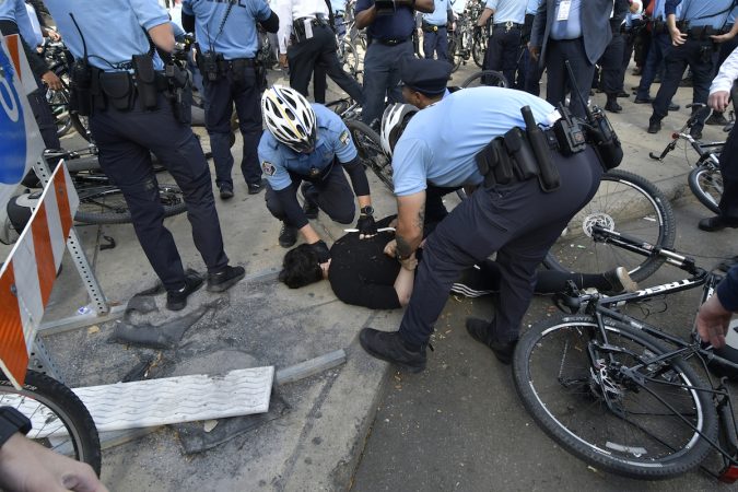 A protester is held on the ground, face down by an officer