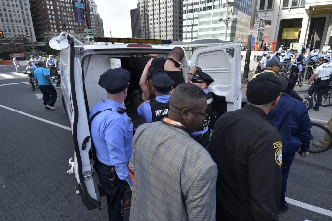 Officers load protesers into a police wagon