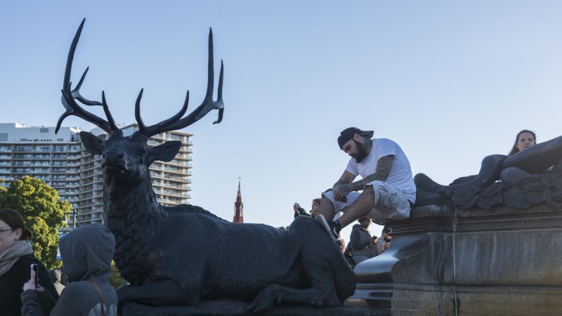 A man sits atop a statue of a stag near the Art Museum