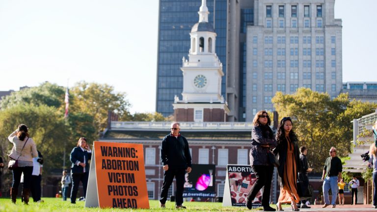 Visitors of Independence Mall in Philadelphia walk past signs both depicting and warning of graphic images. Created Equal, the anti-abortion group that is Columbus, Ohio-based, sponsored the protest. (AP Photo/Matt Rourke)