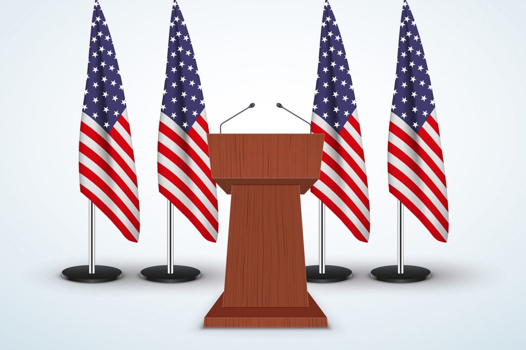 bigstock-153065078fixx1200 Wooden Podium Speaker Tribune with United States flags on background.