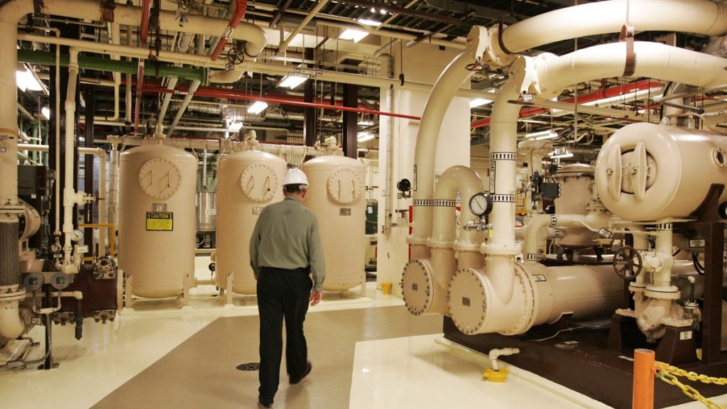 l_ap_100225013802 A man in a hard hat walks past equipment in the turbine building of a nuclear energy facility