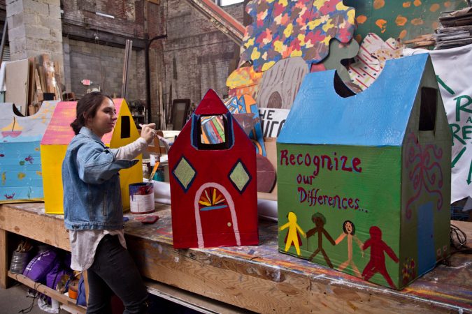 Spiral Q apprentice Laura Beery paints houses for Peoplehood parade participants to wear on Saturday. (Kimberly Paynter/WHYY)