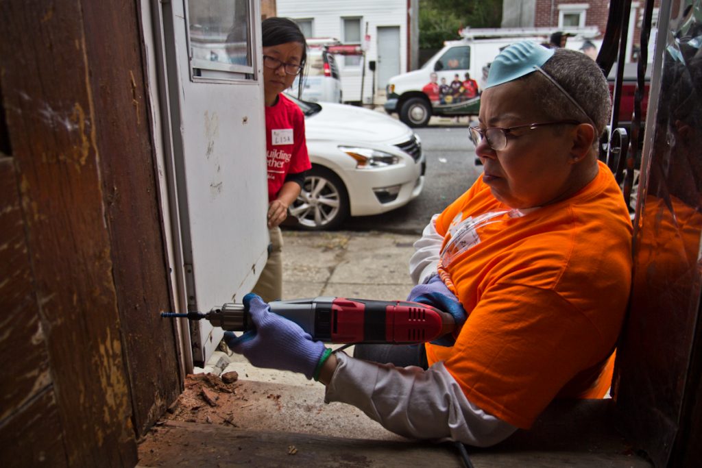 rebuild-2 A woman uses a hand drill as another woman looks on