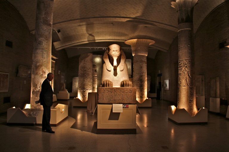 A man looks at a red granite sphinx in the Egypt gallery at the Penn Museum