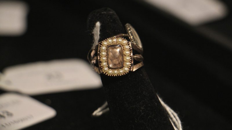 Pearls frame the woven hair of the deceased in this gold and enamel mourning ring from 1806.