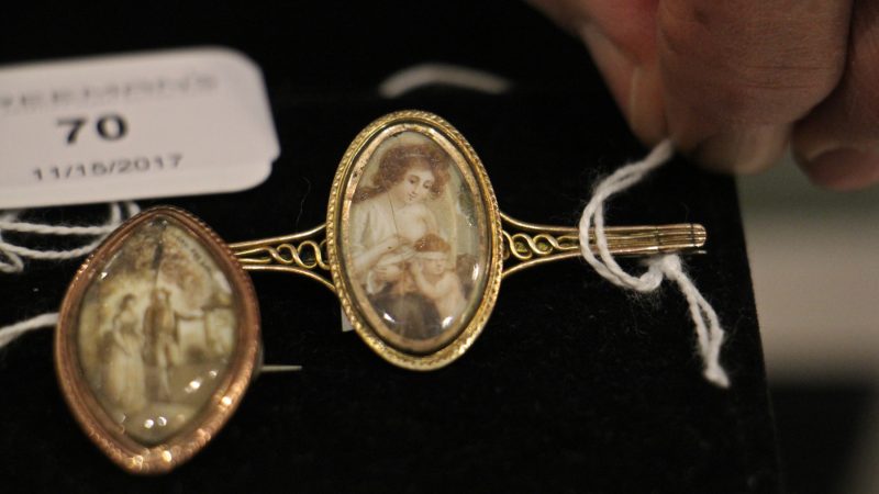 A mourning pin from the late 18th or early 19th century shows a woman blindfolding Cupid. Whether the pin depicted the mourner or the mourned is unknown.