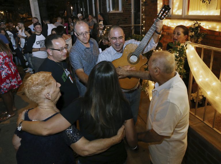 Cousin of the bride, Vincenzo Longo, plays the guitar as a crowd gathers in the street outside the decorated home of Susan and Larry Longo during the Italian wedding serenade for their daughter Stephanie Longo, Saturday, Oct. 7, 2017, in Philadelphia, Pa.  An Italian wedding tradition is alive and well in south Philadelphia, where young couples are transforming something old into something new with their take on the wedding serenade. (Mel Evans/AP Photo)