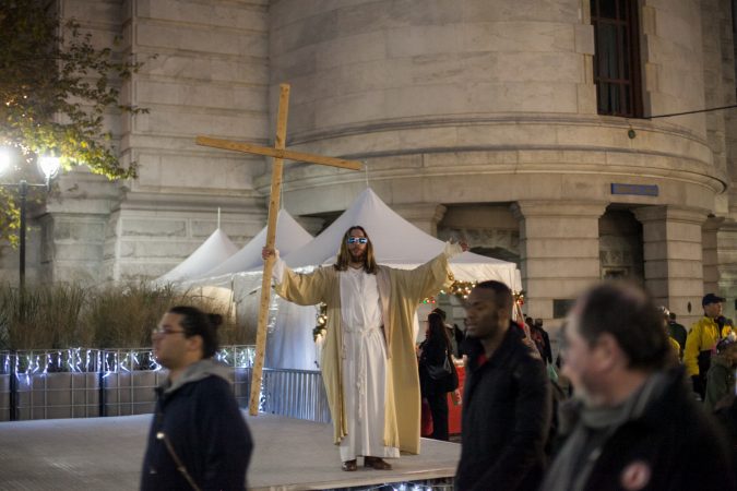 The man who calls himself Philly Jesus quotes scripture in the City Hall courtyard before the Christmas tree lighting ceremony Friday evening. (Brad Larrison for WHYY)