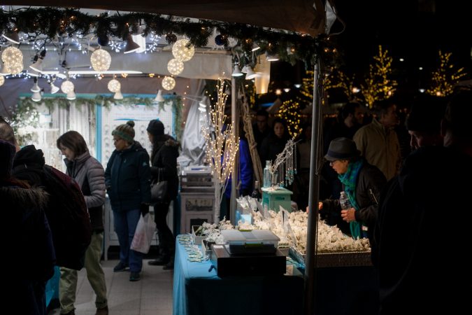 Shoppers browse a stand at the Christmas Village in Dilworth Park Friday evening. (Brad Larrison for WHYY)