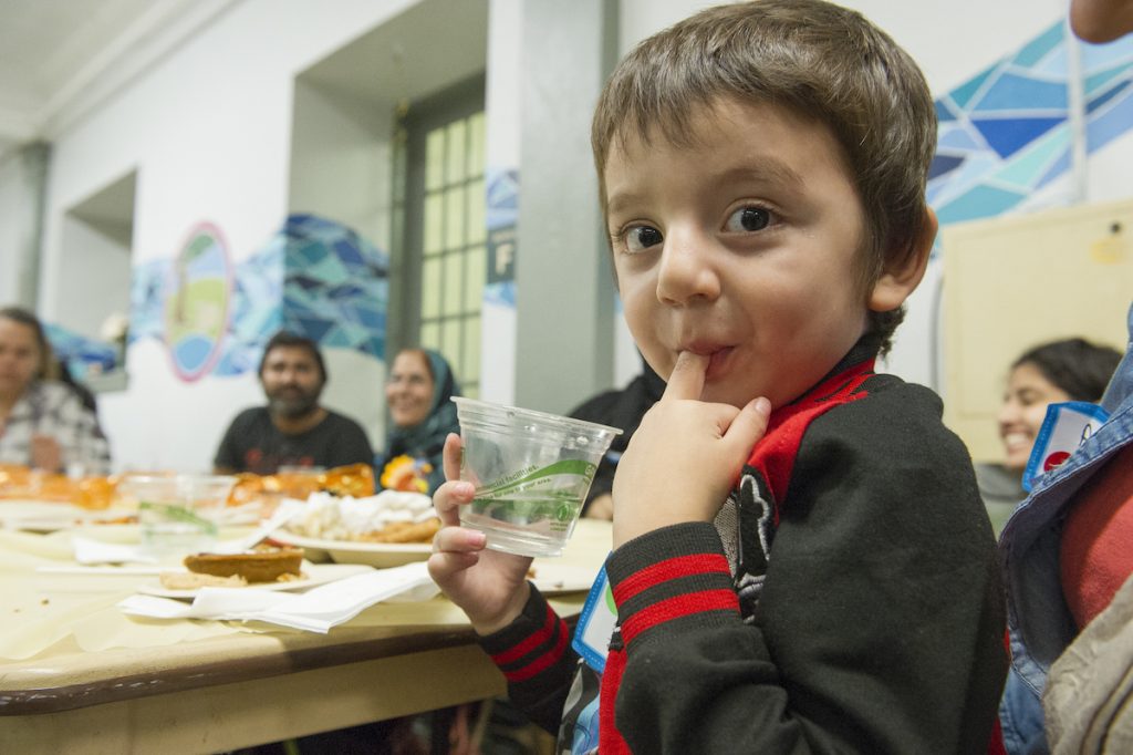 Hasib licks his fingers during the Annual Thanksgiving Celebration dinner. (Jonathan Wilson for WHYY)