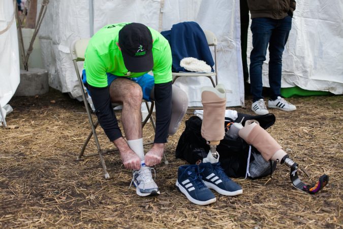 Evan Freiberg changes his shoe and his prosthetic before the Rothman Institute 8k Saturday. The 43-year-old is diagnosed with leiomyosarcoma, a form of cancer, and competed after losing the bottom portion of his left leg to the disease. (Brad Larrison for WHYY)