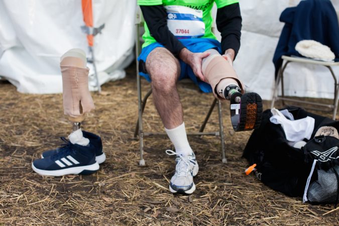 Evan Freiberg finishes putting on his running prosthetic before the Rothman Institute 8k Saturday. The 43-year-old is diagnosed with leiomyosarcoma, a form of cancer, and competed after losing the bottom portion of his left leg to the disease. (Brad Larrison for WHYY)