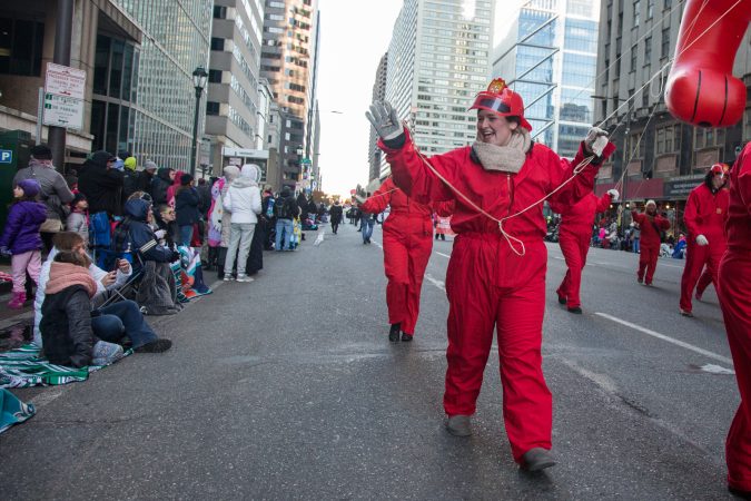 A balloon wrangler for Clifford the Big Red Dog waves at the crowd at the 98th annual Philadelphia Thanksgiving Day Parade, November 23, 2017. (Emily Cohen for WHYY)